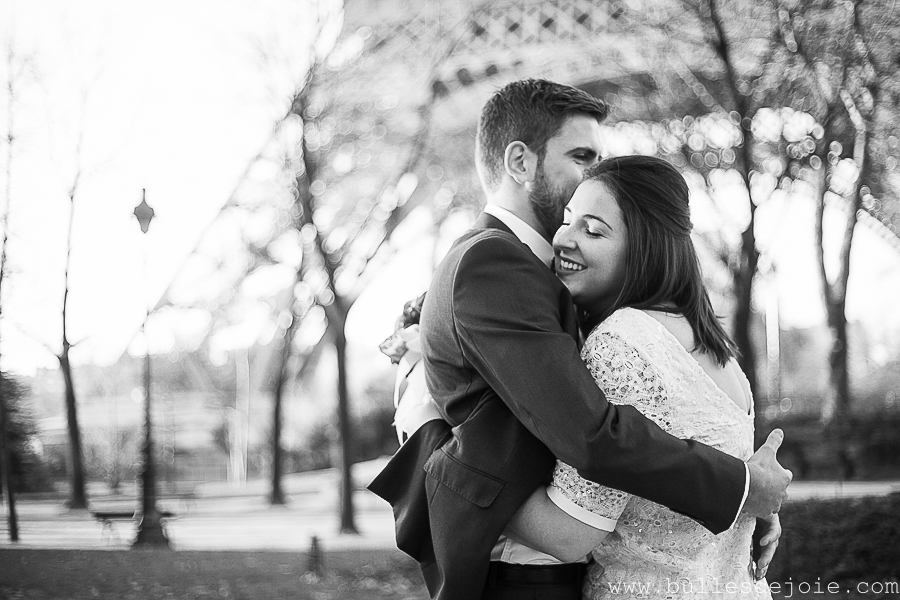 Couple d'amoureux enlacés devant la Tour Eiffel, en noir et blanc | Bulles de Joie Photographie, photographe Paris