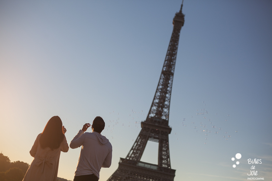 Couple au pied de la Tour Eiffel soufflant des bulles de savon
