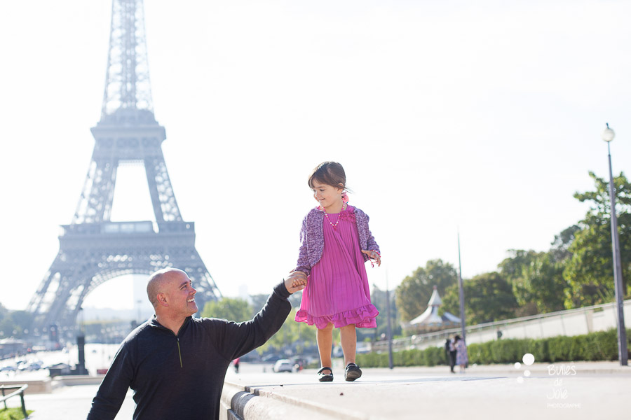 Summer family photoshoot. Girl holding her dad's hand in front of the Eiffel Tower in Paris.